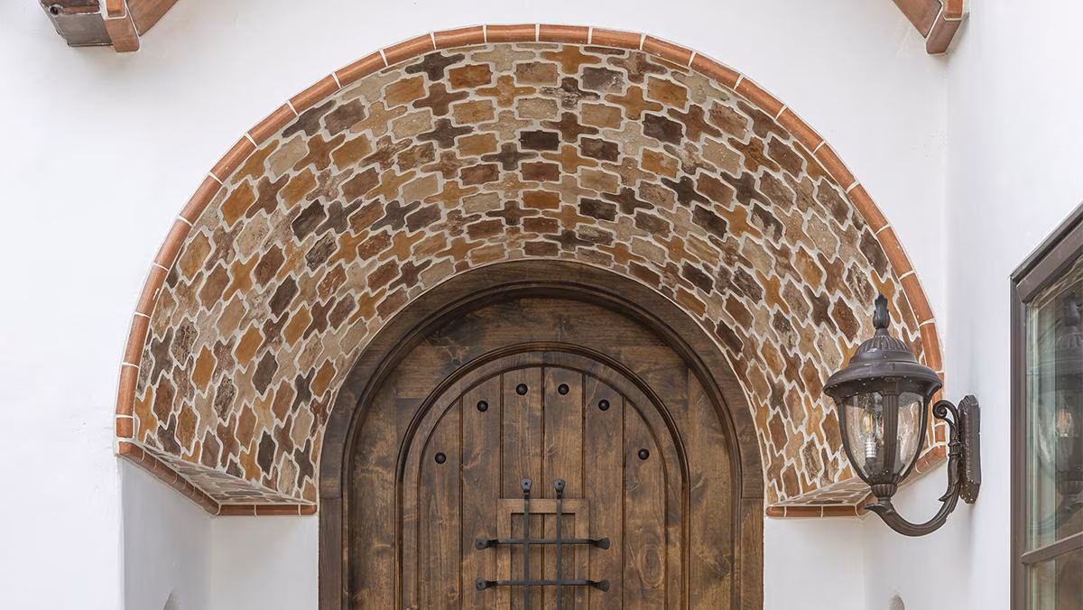 Handcrafted decorative tile arch above a wooden entry door at the Santa Monica Residence project by Famosa Tile.