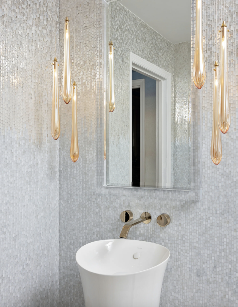 Luxury primary bathroom featuring white mosaic tile walls, brass pendant lighting, and a freestanding vanity, showcasing a coordinated material system for bathroom design.
