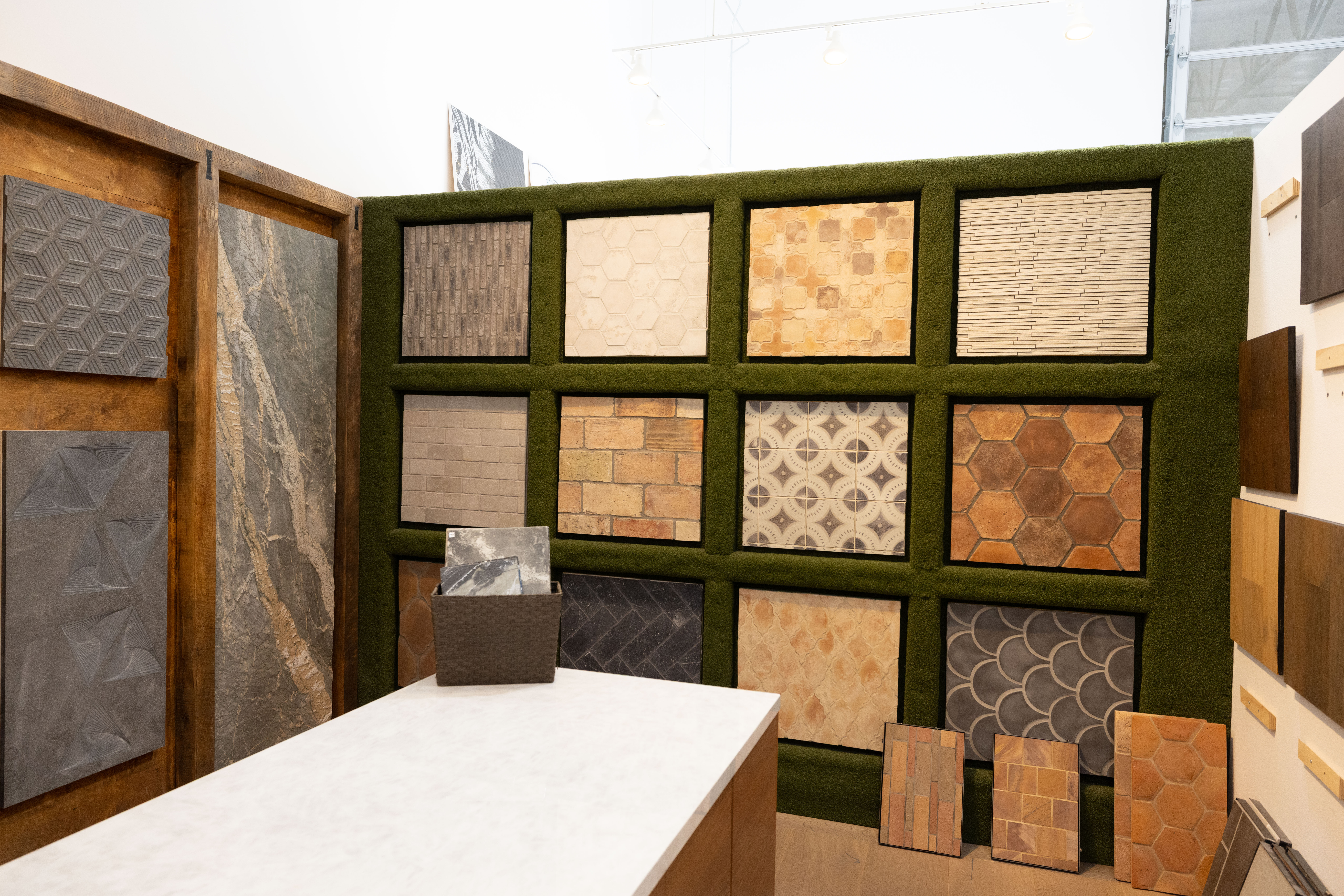 Famosa Tile Costa Mesa showroom displaying new fall 2026 tile arrivals in deep green, terracotta, warm charcoal, and earthy limestone tones.